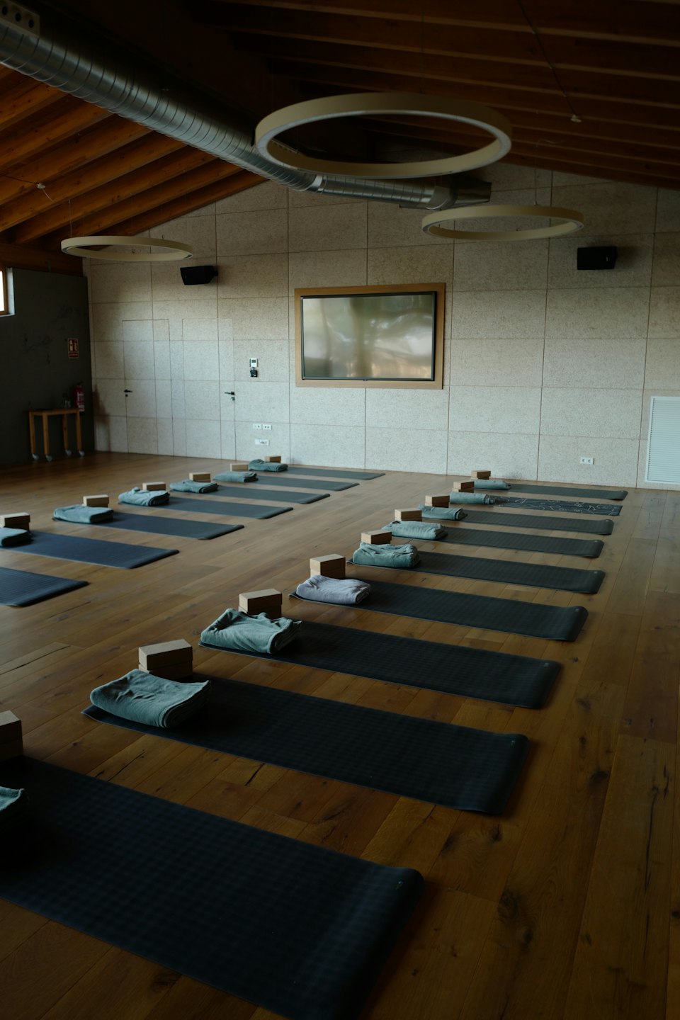 Matlar, bloklar ve havluların düzenli bir şekilde yerleştirildiği yoga stüdyosu.