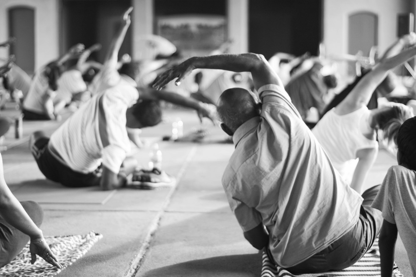 İnsanlar kapalı alanda yapılan bir yoga dersinde esneme hareketleri yapıyor.